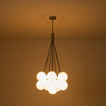 Exuding modern mid-century charm, this chic cluster chandelier effortlessly enhances any interior space with its stylish design. Crafted with a harmonious fusion of metal and opal globes, it creates a captivating visual display while illuminating the room from multiple angles. The opal glass shades, paired with 13 E26/E27 bulbs (bulbs not included), cast a warm and inviting glow throughout, perfect for creating a welcoming ambiance.
